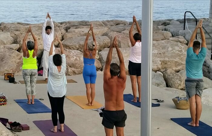 People practicing outdoor yoga by the sea in Menton